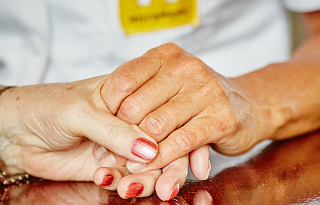 Hilfswerkerin hält Hand ihrer Kundin 