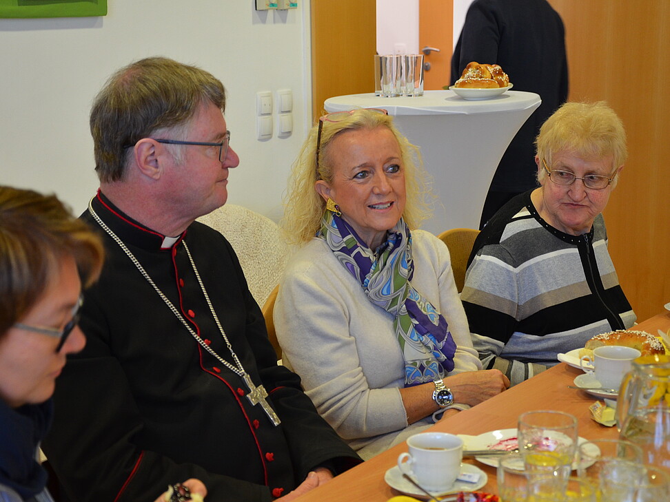 1 Mann und 3 Frauen sitzen an einem Tisch und trinken Kaffee